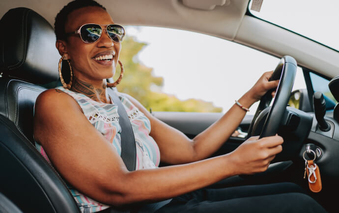 Woman in the drivers seat of a car and holding the steering wheel